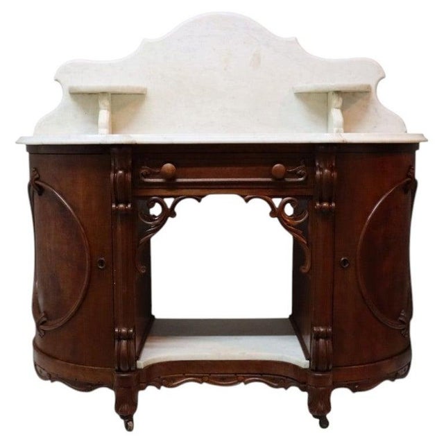 This antique server desk, dating to approximately 1880, is crafted from carved walnut and burl wood, featuring a...