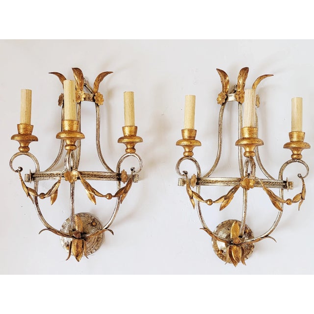 Stunning large pair of Regency Style silver and gold gilt wall sconces with laurel leaf swag and rosettes motifs. It...