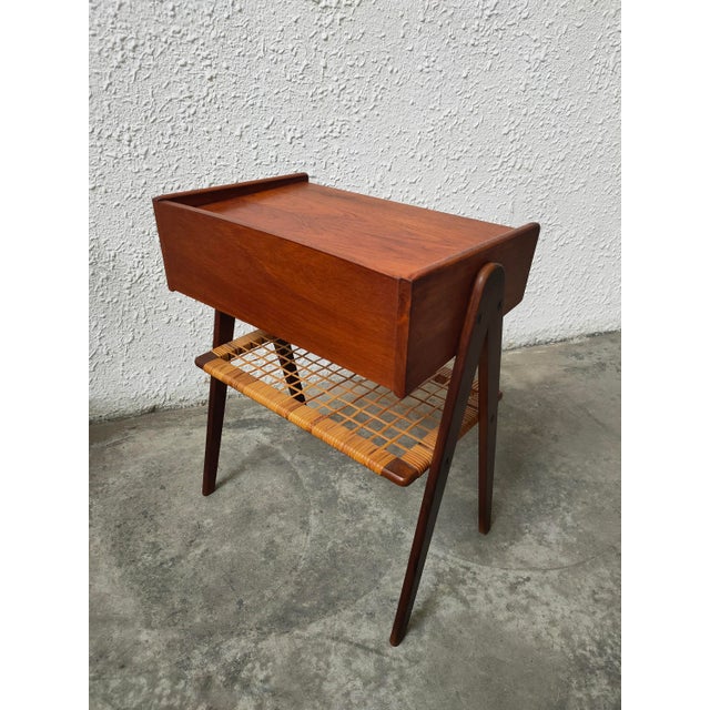 : Teak bedside table with one drawer and a wicker shelf, designed by Søren Rasmussen in the 1960s. The teak wood gives it...