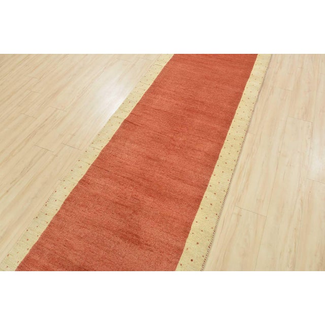 A contemporary Gabbeh runner hand-knotted with an all-wool pile on a cotton foundation. This oriental rug features a solid...