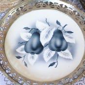 A beautiful set of silver plates with one being a handpainted pear plate. The pair plate is on blue and white ceramic from...