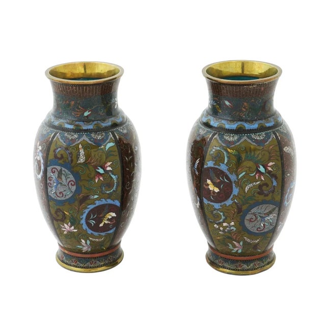 A pair of symmetrical antique Japanese, late Meiji era, enamel over brass vases. The exteriors of the urn shaped vases are...