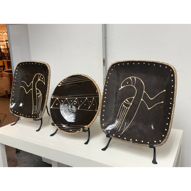 Design Plus Gallery presents a Set of Three Ceramic Platters + Stands. Two rectangular platters depict stylized birds...
