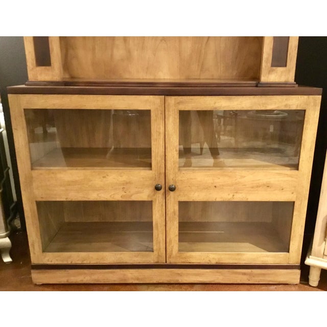 Stylish Transitional Wood Collectors bookcase finished in a contrasting blonde wood and walnut, two glass doors revealing...
