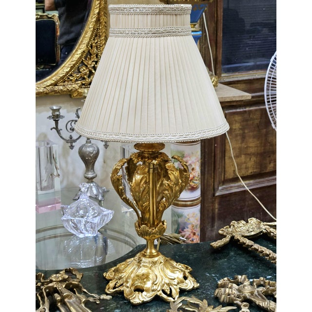 This delicate French-style table lamp combines an elegant gold leaf and bronze-finished base with a softly sculpted...