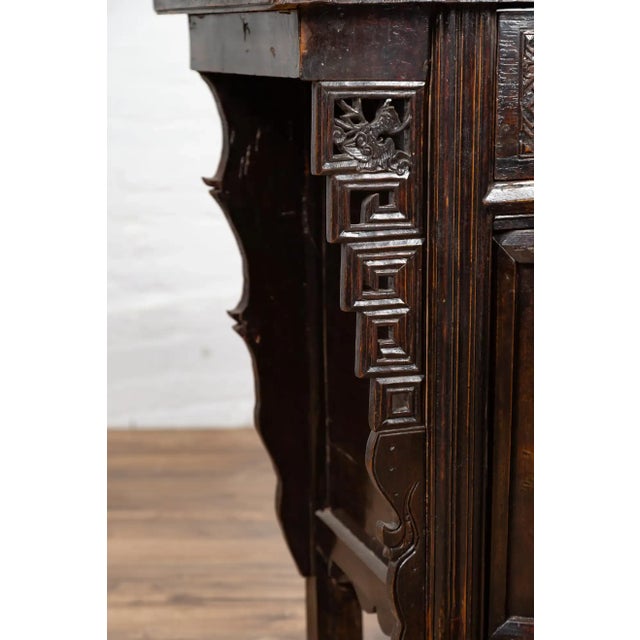 A Chinese Ming Dynasty style wooden butterfly cabinet from the 19th century, with carved spandrels, drawers, doors and...