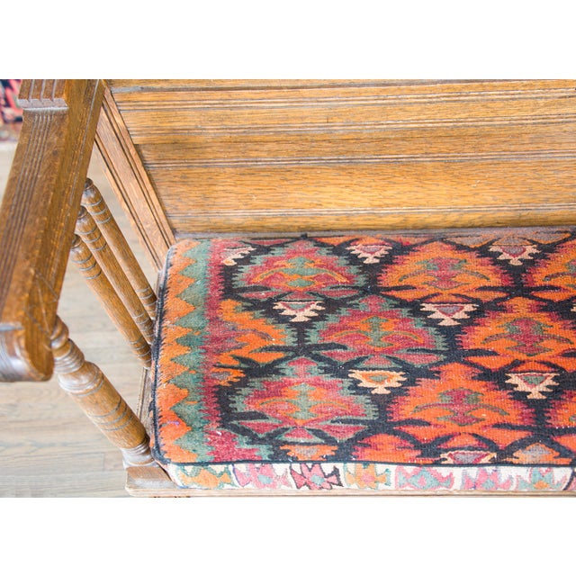 An early 20th century Danish oak bench with paneled back, turned arm supports and legs, with a newly upholstered seat...