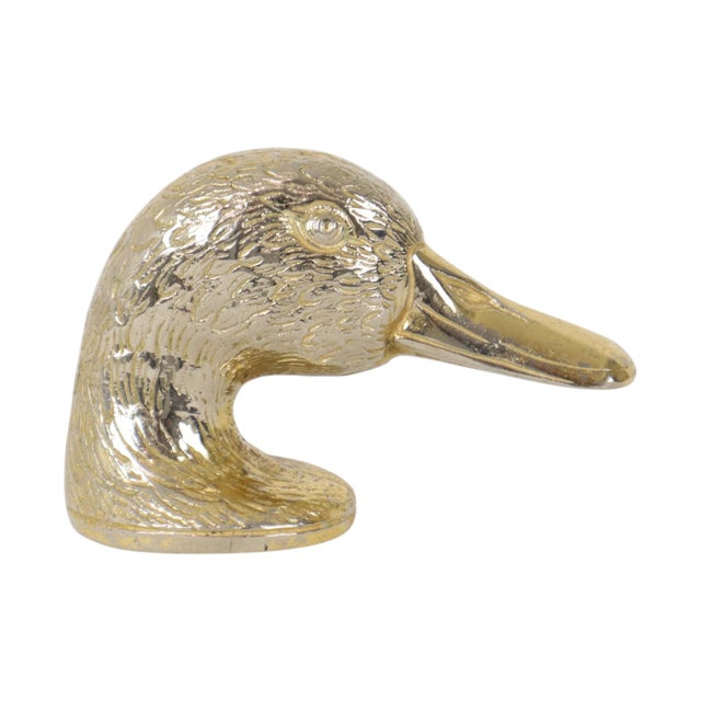 Vintage metal bottle opener shaped like a duck's head, made of silver-colored metal with a gold-colored finish; dates from...