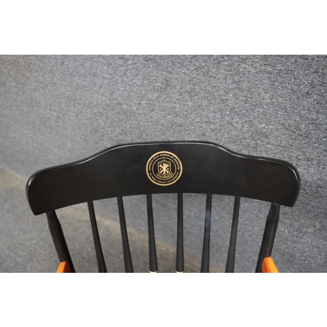 Classic Windsor-style armchair finished in black with contrasting natural maple arms and gold accent turnings. The crest...