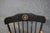 Classic Windsor-style armchair finished in black with contrasting natural maple arms and gold accent turnings. The crest...