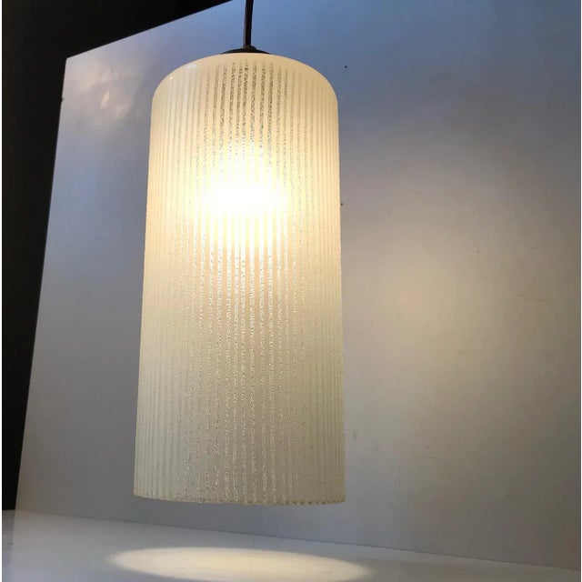 - Cylindrical pin-striped pendant lamp - Made from partially frosted hand-blown single layered glass - The top is made...