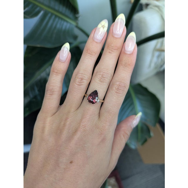 This elegant Tourmaline ring features a vibrant 3.7ct pear-cut rubellite tourmaline measuring 13x8mm, set in solid 14K...
