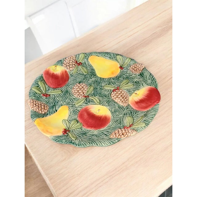The Vintage 1991 Fitz & Floyd Woodland Fruit Majolica Platter is a round ceramic piece featuring a colorful, all-over...