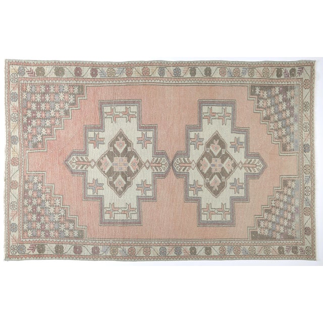 This vintage tribal Turkish rug a beautifully muted palette of soft peach, sand, taupe, and dusty lavender, giving it a...