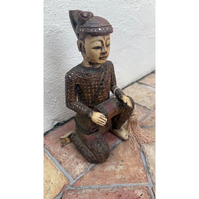 This finely detailed hand-carved Chinese wooden figural sculpture depicts a seated musician holding a small drum, rendered...