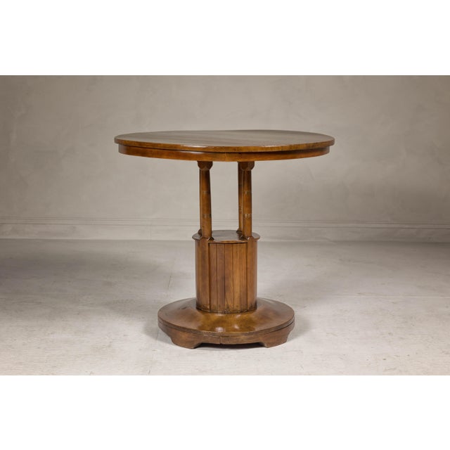 A Midcentury wooden side table with round top, column-shaped supports and tambour base. This Midcentury wooden side table...