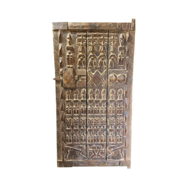 This vintage Dogon granary door from Mali features intricate carved relief figures— standing Nommo ancestors , breasts...