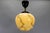 Small-scale german art deco pendant light in marbled ivory color glass with warm ambient illumination and bakelite...