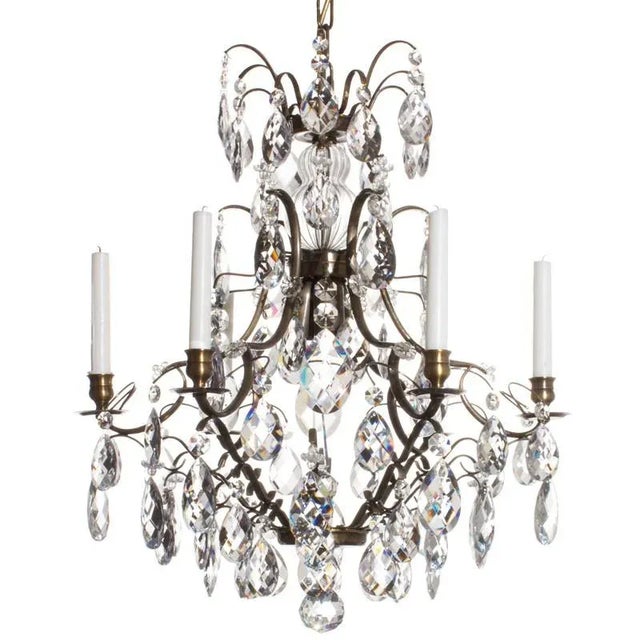 A light brass cognac coloured 6 arm baroque style chandelier with hand cut almond shaped crystals. At the bottom of this...