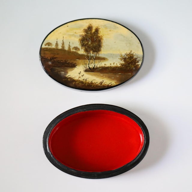 Vintage Soviet Fedoskino lacquer box of oval form, hand-painted with a landscape showing water, low shoreline, clustered...