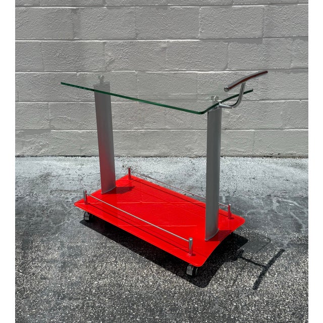 A playful take on classic mid-century form, this bar cart pairs a vivid lacquered red lower shelf with a floating glass...
