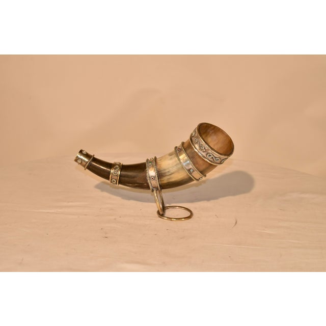 Circa 1920's drinking horn on stand. The horn is decorated with brass metal bands, which have decorative beads in the...