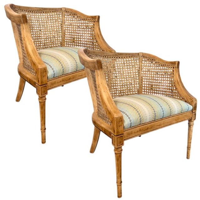 A striking pair of cane barrel back lounge chairs featuring beautifully woven cane panels and a natural wood finish that...