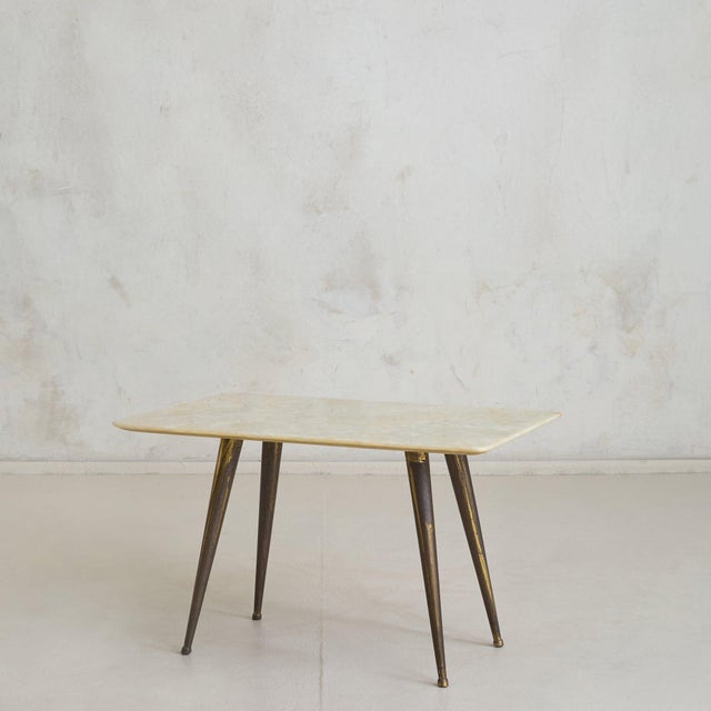 An Italian coffee table from the 1950s, composed of a softly rounded onyx top resting on tapered brass legs. The slab is...