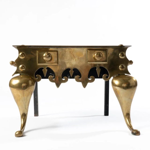 A brass footman with frieze features, knob fixtures and handles on each side. The stand is raised on cabriole front legs.