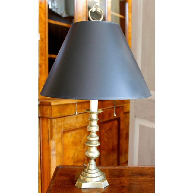 A sturdy Victorian era brass candlestick adapted into a lamp. Black "parchment" shade with lovely gold textured lining....