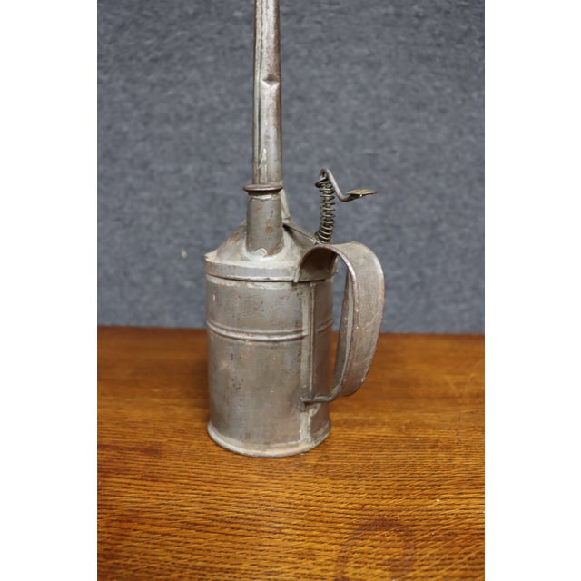 Antique industrial oil can constructed of tin with a cylindrical body, long tapered spout, side handle, and spring-...