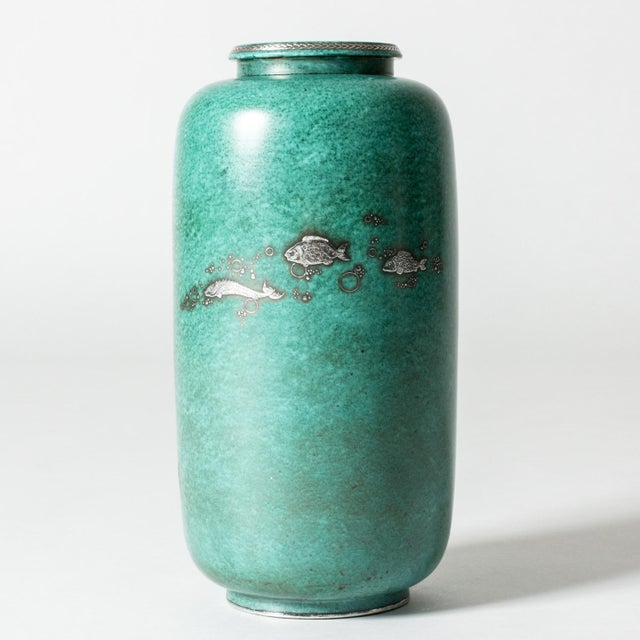 Beautiful stoneware “Argenta” vase by Wilhelm Kåge in a cylinder form. Decorated with a mermaid swooning among flowers and...