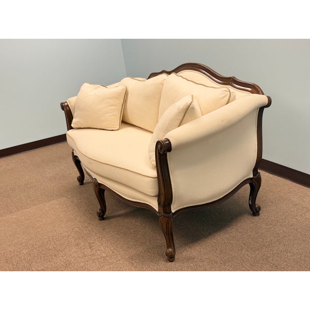 Elegant traditional upholstered sofa with a carved dark-wood frame, rolled arms, and classic Neoclassical detailing....