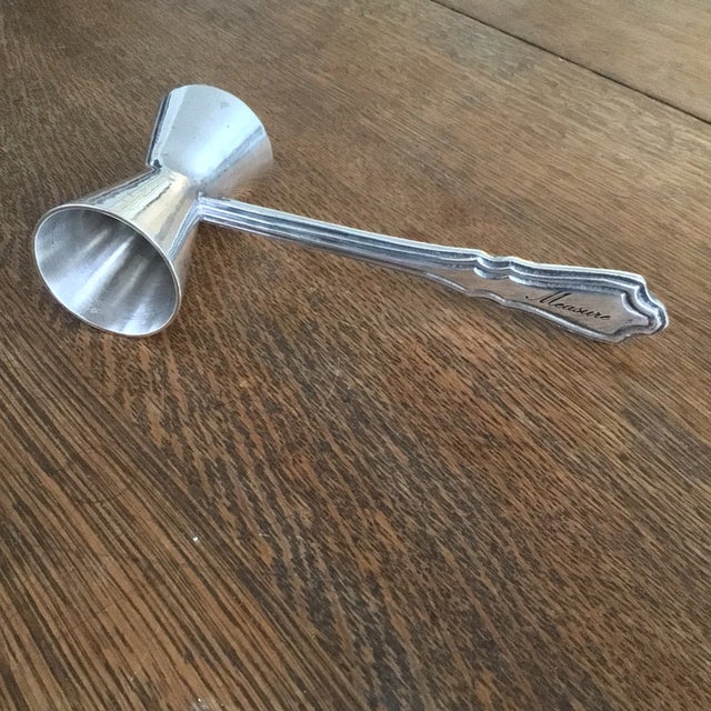 French nickel silver double jigger with a etched handle that reads Measure on both sides at the end of the handle. The...