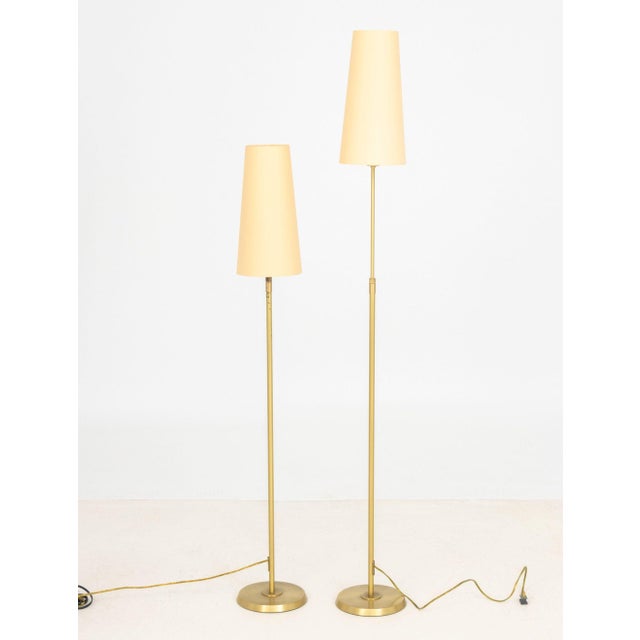 Pair of Holtkoetter Leuchten Brushed Brass Floor Lamps, each with beige shade, marked underside. 51.5" H x 8" Diameter....