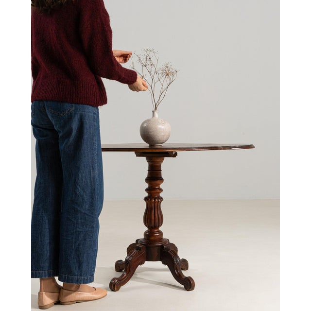 Tilt-top pedestal table in Rich Mahogany. The rich mahogany surface highlights round top, turned tripod base with scroll...
