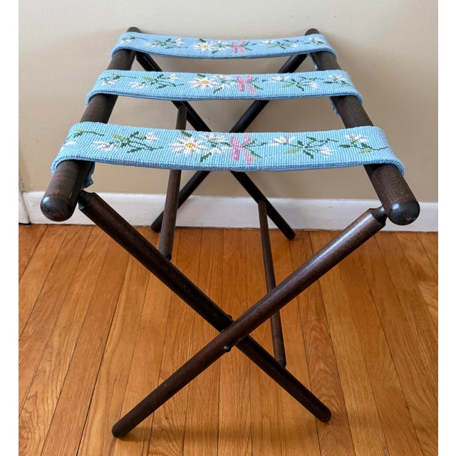 A midcentury wooden luggage or serving tray rack stand with blue needlepoint straps. Folds for easy storage. Will be...