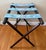 A midcentury wooden luggage or serving tray rack stand with blue needlepoint straps. Folds for easy storage. Will be...