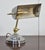 Adjustable Bankers desk lamp, the silvered circular stepped base and brass pivoted sweeping arm supporting adjustable...