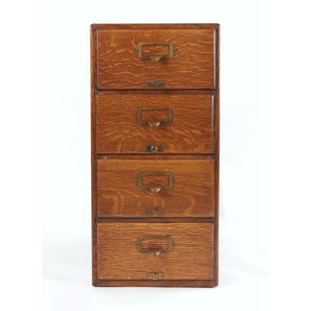 20th century four dovetailed drawer oak desktop filing cabinet with brass hardware. The drawer interiors have built in...
