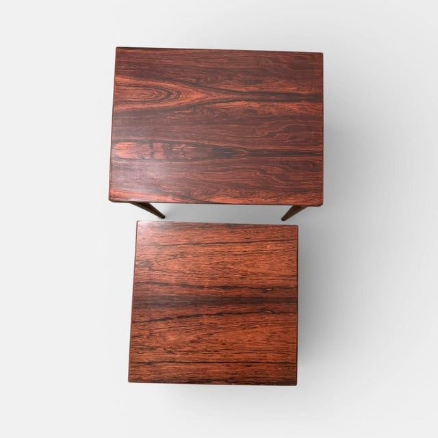 A set of three danish nesting tables crafted in palisander, produced in denmark circa the 1960s. the tables are designed...