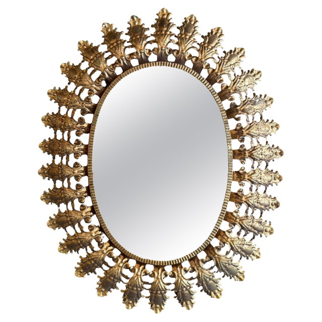 Spanish 1950s gilt metal oval sunburst mirror with tight connected leaf pattern frame.