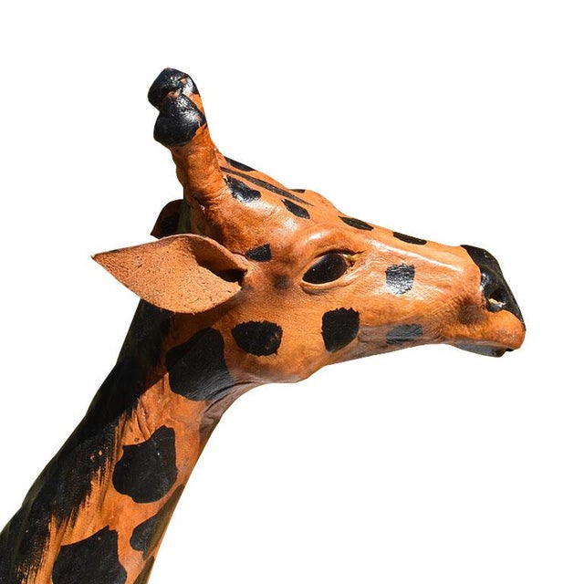 A tall paper mache giraffe in black and brown with leather ears and glass eyes. We see this fun piece in a nursery or in a...