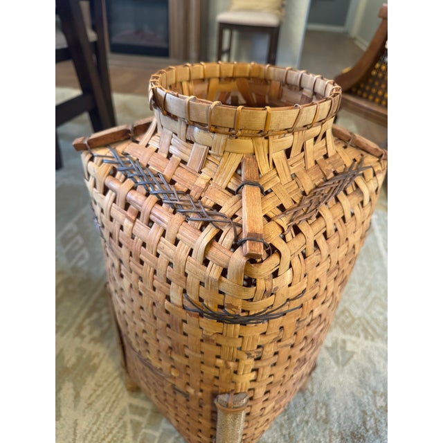 Architectural handwoven basket vessel crafted from split wood, featuring a sculptural rectangular form, raised footed...