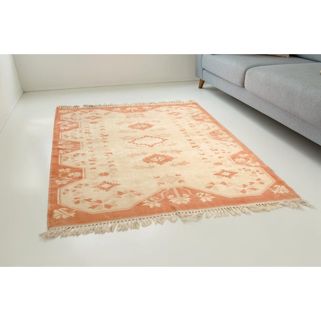 This is a vintage Turkish Oushak rug from the Mid 20th Century. The piece was hand-knotted.