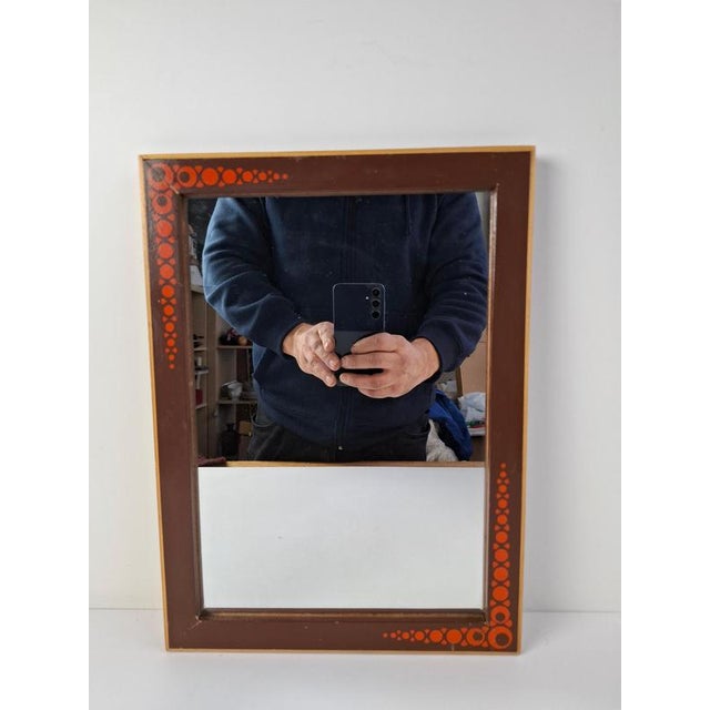 A mid-century wall mirror produced in 1960s Czechoslovakia, featuring a wooden frame adorned with stylized red circular...