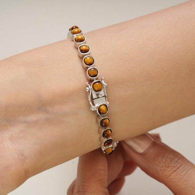 Handcrafted in 925 sterling silver, the bracelet features a seamless row of cushion-cut Tiger’s Eye gemstones, each...