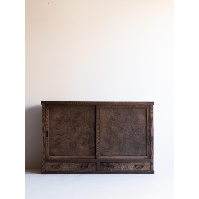 This cha dansu tea cabinet was crafted in Japan during the Taishō to early Shōwa period, using richly grained keyaki...