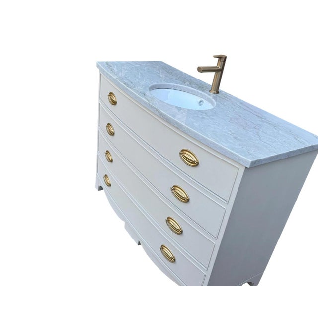 Elegant vintage bow-front dresser thoughtfully converted into a distinctive single-sink bathroom vanity. The cabinet...