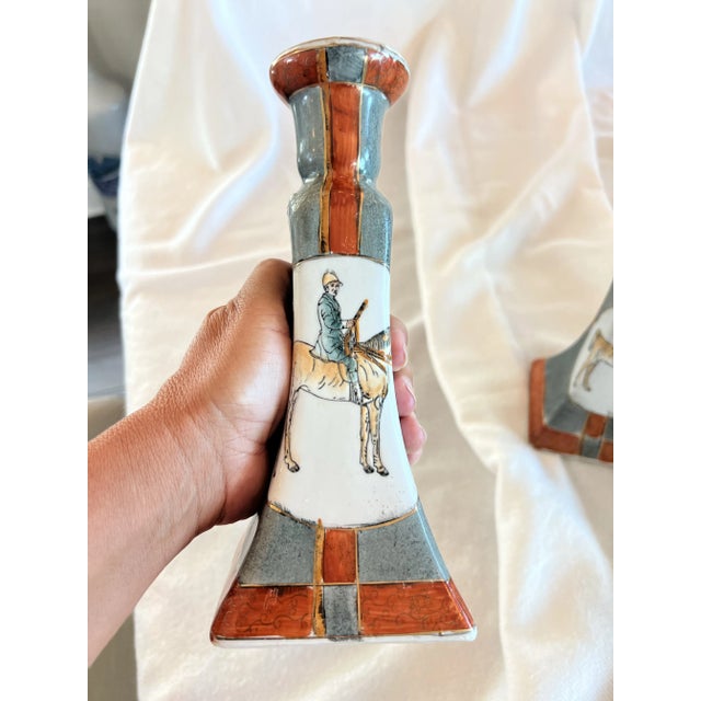 A pair of vintage candlesticks with an equestrian theme. Horse and rider proudly displayed on the front. There is gilt...